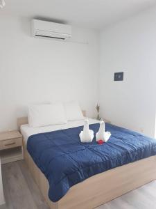 dos cisnes sentados sobre una cama azul en Apartmani Nikša Divić - Villa Mateo, en Baška Voda