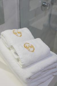- deux serviettes blanches avec des bagues en or dans la salle de bains dans l'établissement Aparthotel Pietroasa, à Buzău