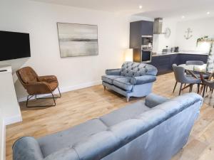 un soggiorno con divano blu e sedie di The Grange Cottage 1 a Grimsby