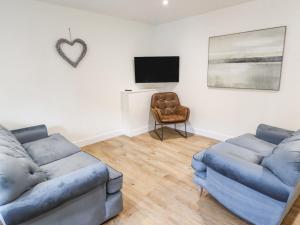sala de estar con 2 sofás azules y TV en The Grange Cottage 1 en Grimsby