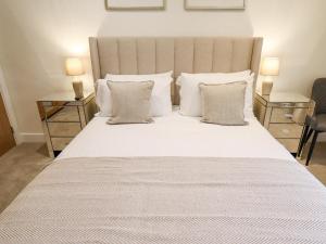 1 dormitorio con 1 cama blanca grande y 2 mesitas de noche en The Grange Cottage 1 en Grimsby