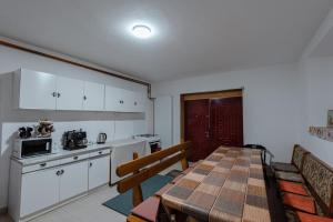 a kitchen with a table and a dining room at Pensiunea La Maison Verte in Pietroasa