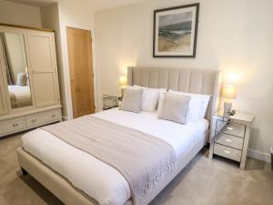 a bedroom with a large white bed and a mirror at The Grange Cottage 2 in Grimsby
