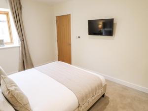 a bedroom with a bed and a television on a wall at The Grange Cottage 2 in Grimsby