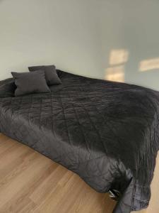 duże czarne łóżko na drewnianej podłodze w obiekcie Prie Vilneles Apartment w Wilnie