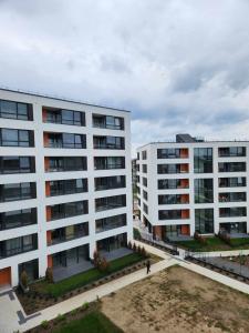 zwei weiße Gebäude mit Leuten, die vor ihnen laufen in der Unterkunft Prie Vilneles Apartment in Vilnius