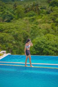 a woman standing on a paddle board in the water at Palawan Swing in Puerto Princesa City