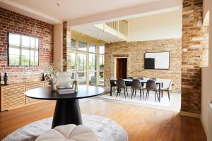 un soggiorno con tavolo e parete in mattoni di The Chelmsford Hideaway - Spacious 5BDR House with Patio + Garden a Chelmsford