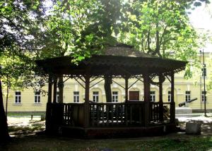 a wooden gazebo in front of a white building at Picturesque apartment into antique fortress in Daugavpils