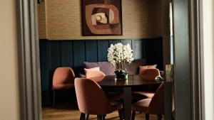 uma sala de jantar com uma mesa com cadeiras e um vaso de flores em The Lawrance Luxury Aparthotel - Harrogate em Harrogate