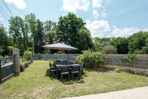 a table and chairs with an umbrella in a yard at Le Verdier - Charmante maison pour 10 avec jardin in Peschadoires