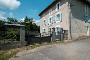a building with a gate and an umbrella next to it at Le Verdier - Charmante maison pour 10 avec jardin in Peschadoires +8 photos