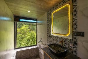 a bathroom with a sink and a mirror and a window at Dharamalaya by StayVista - The Eco Home in Dharamshala