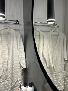 a mirror reflecting two white shirts in a bathroom at Байзакова 133, новостройка in Pavlodar
