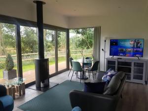 sala de estar con sofá, TV y mesa en Landscape, New Eco Lodge Flatford Mill en East Bergholt