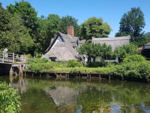 ein strohgedecktes Cottage neben einem Fluss in der Unterkunft Landscape, New Eco Lodge Flatford Mill in East Bergholt