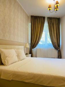 Schlafzimmer mit einem großen weißen Bett und einem Fenster in der Unterkunft Gloria’s Place in Bukarest