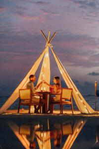 een man en vrouw aan een tafel onder een tent bij Nova Maldives in Dhangethi