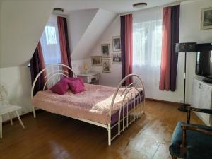 Un dormitorio con una cama con almohadas rosas. en Strażnica Komtura, en Mikołajki