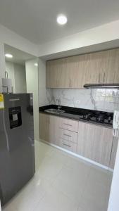 eine Küche mit einem Kühlschrank aus Edelstahl und Holzschränken in der Unterkunft Apartamento muy cerca al Mar de 3 habitaciones in Cartagena de Indias