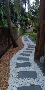 a walkway with rocks and trees in a park at Krishnendu Homestay outer ring road north nada guruvayur in Guruvāyūr