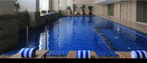 a large swimming pool with chairs in a hotel room at Condo hotel MAKATI GREENBELT in Manila