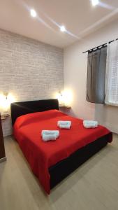 a bedroom with a red bed with two towels on it at La Coccinella in Nettuno