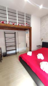 1 dormitorio con 1 cama roja y 2 toallas blancas en La Coccinella en Nettuno