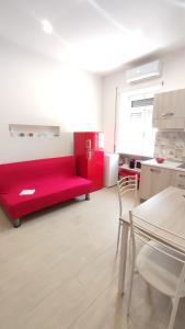 un sofá rojo en una habitación con mesa y sillas en La Coccinella, en Nettuno