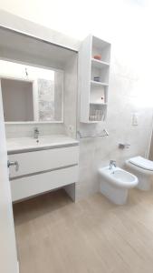 bagno bianco con lavandino e servizi igienici di La Coccinella a Nettuno
