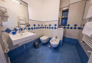 a blue and white bathroom with a sink and a toilet at Tra le Mura in Polignano a Mare