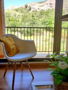uma cadeira branca com uma almofada amarela sentada em frente a uma janela em Acogedor apartamento en Anguiano em Anguiano