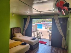 a bedroom with two beds and a door to a patio at OCEANBOYS INN in Perhentian Islands
