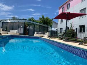 a swimming pool with an umbrella next to a building at Kyriad Montpellier Aéroport - Parc Expo in Mauguio