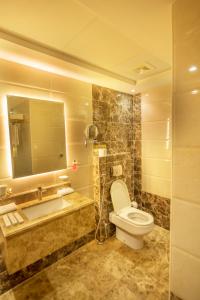 ein Badezimmer mit einem WC, einem Waschbecken und einem Spiegel in der Unterkunft Sparrow Apartments Hotel in Dschidda