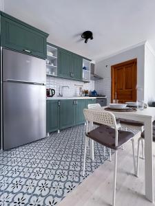 a kitchen with green cabinets and a white table and chairs at Assos Sizin Ev in Ayvacık