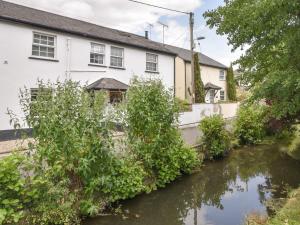 a house with a river in front of it at River Lym Cottage in Lyme Regis
