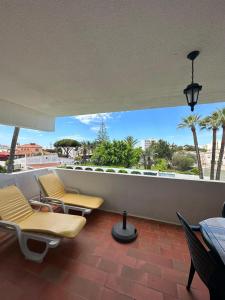 クアルテイラにある2 Bedroom Apartment in Quarteira with Balcony, Pool and Wi-Fi by Centralgarveのヤシの木が植わるバルコニー(椅子、テーブル付)