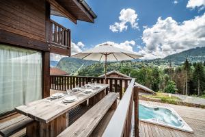 drewniany taras ze stołem i parasolem w obiekcie Chalet Cipolin Morzine - by EMERALD STAY w mieście La Côte dʼArbroz