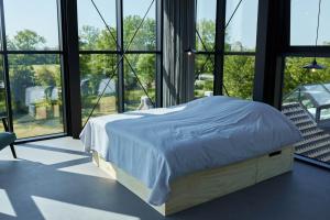 a bed in a room with large windows at Suvelfabryk in Lioessens