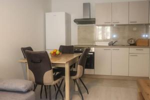 uma cozinha com uma mesa de madeira e cadeiras num quarto em Apartman Matea em Topići
