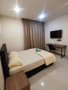 a bedroom with a bed and a desk and a television at Kuching Kozi Square Apartment (II) in Kuching