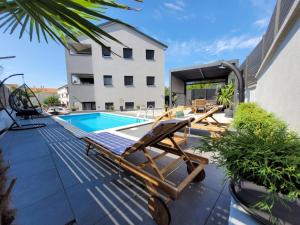eine Terrasse mit Pool und Chaiselongue neben einem Gebäude in der Unterkunft Apartment Lo&Ti in Čižići