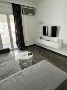 a white living room with a tv and a table at Dimi Guest House in Perea