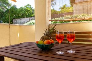 two glasses of wine and a bowl of fruit on a table at Apartman Mia in Palit