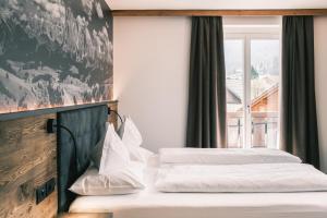 セルヴァ・ディ・ヴァル・ガルデーナにあるKristiania Small Dolomites Hotelの窓付きのホテルの部屋にベッドが2つある