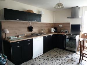 a kitchen with black cabinets and a white stove top oven at La Barboulotte in Saint-Léger-Vauban