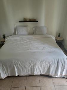 a large white bed with white sheets and pillows at Appartement Proche DisneyLand Paris in Montévrain