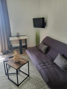 a living room with a purple couch and a table at Appartement Proche DisneyLand Paris in Montévrain