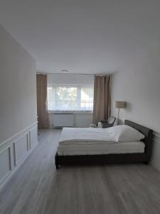 a white bedroom with a large bed and a window at MyCompass Hotel Offenbach in Offenbach